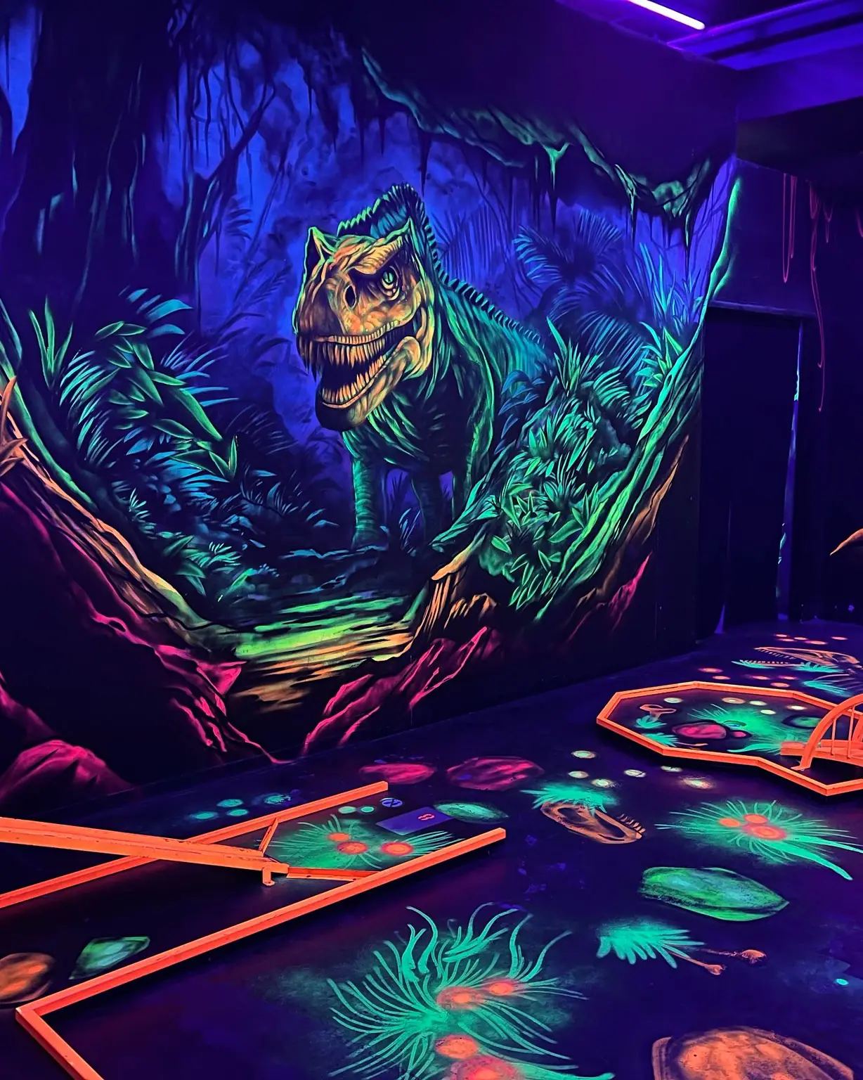 Dinosaurierwelt: T-Rex-Wandbild über einer Minigolfbahn im Schwarzlicht